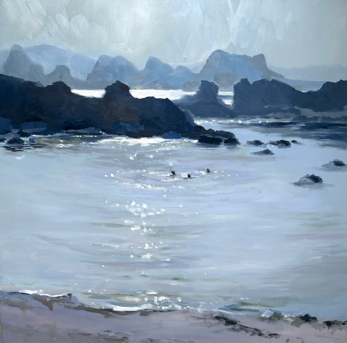 Swimmers in Ballintoy bay in a summer evening with sparkling light